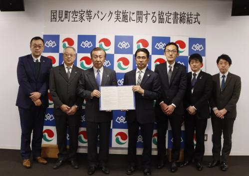 協定を交わした加納会長（中央左）と村上町長（中央右）の写真